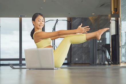 Warrior III yoga pose performed by fitness woman at beach.