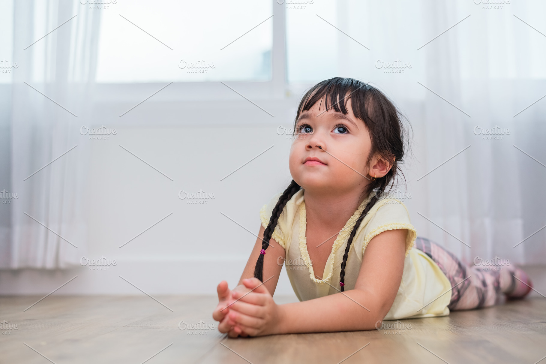 Little girl lying and looking up in home. People and lifestyles ...