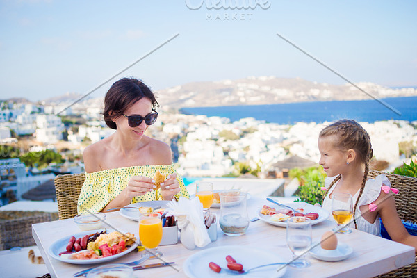 Family Having Breakfast At Outdoor Cafe With Amazing View On Mykonos Town High Quality People Images Creative Market