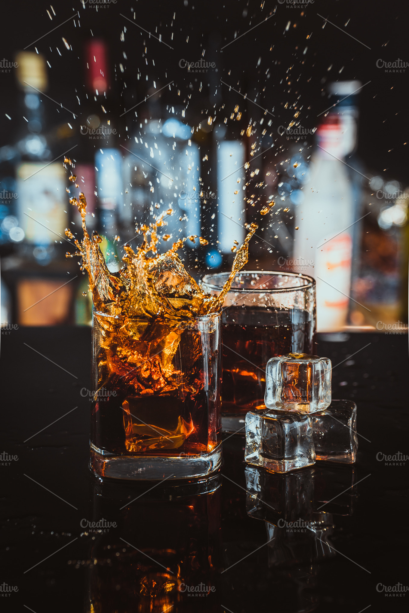 Two glasses of whiskey on a blurred background bar containing alcohol