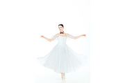 Ballerina in white dress posing on pointe shoes studio background stock