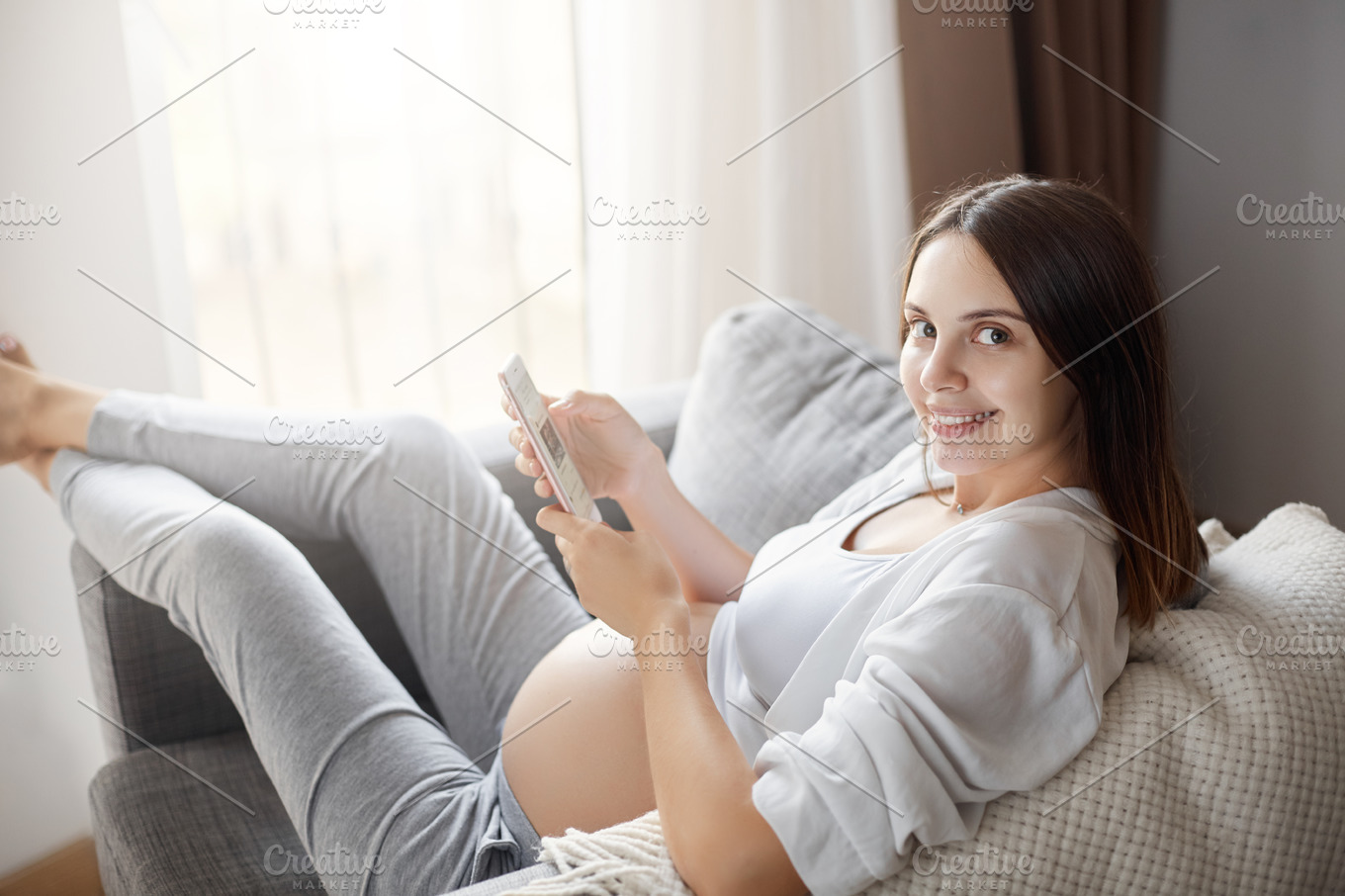 Portrait Of Young Pregnant Lady Using A Smart Phone Staying Home