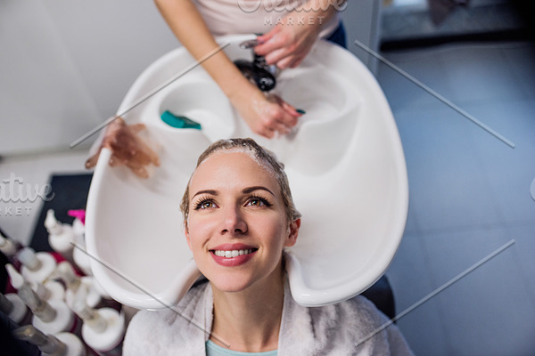 Unrecognizable professional hairdresser washing hair to her beau stock ...