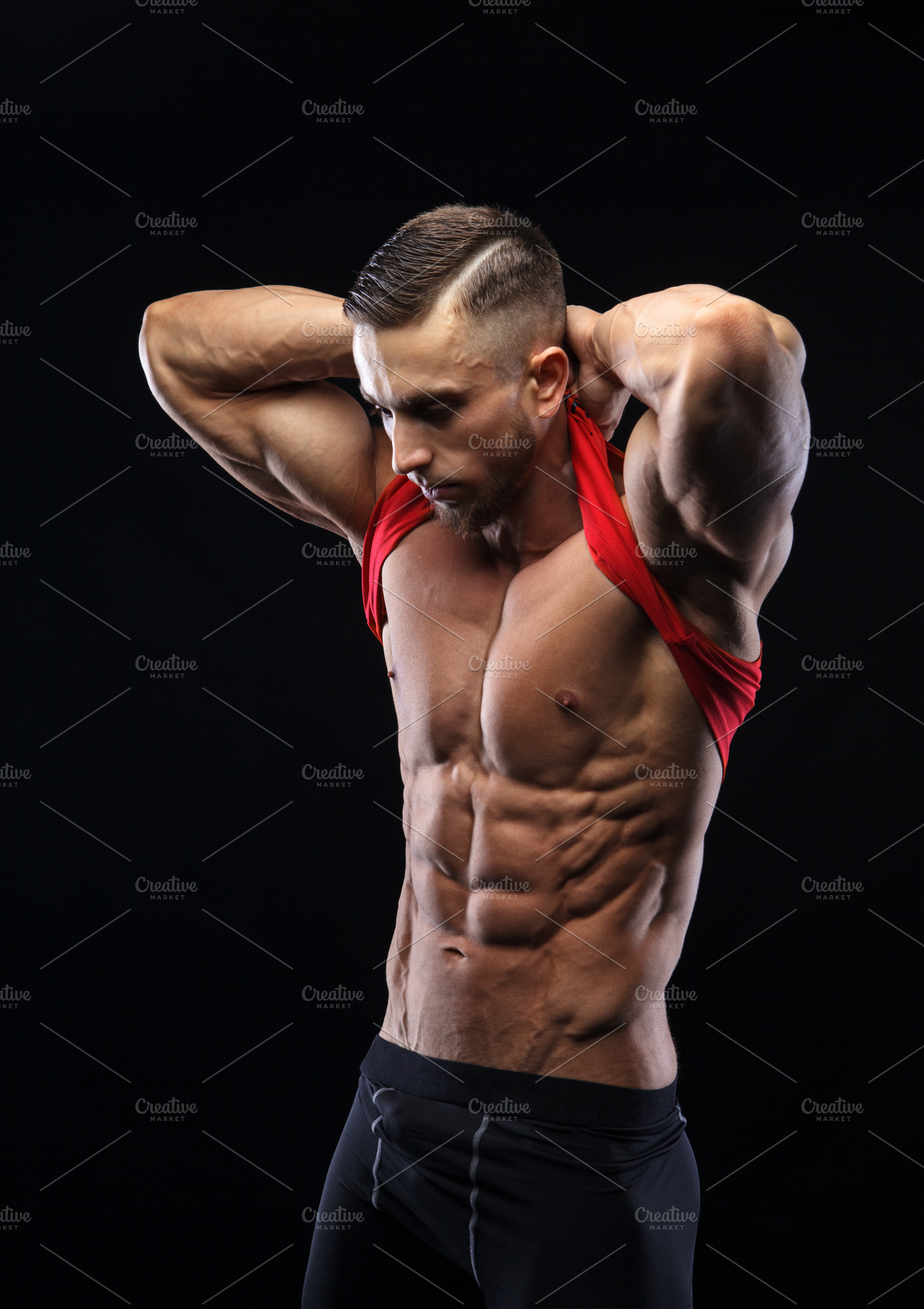 Cute young sports man in red tshirt shows relief abdominal muscles ...