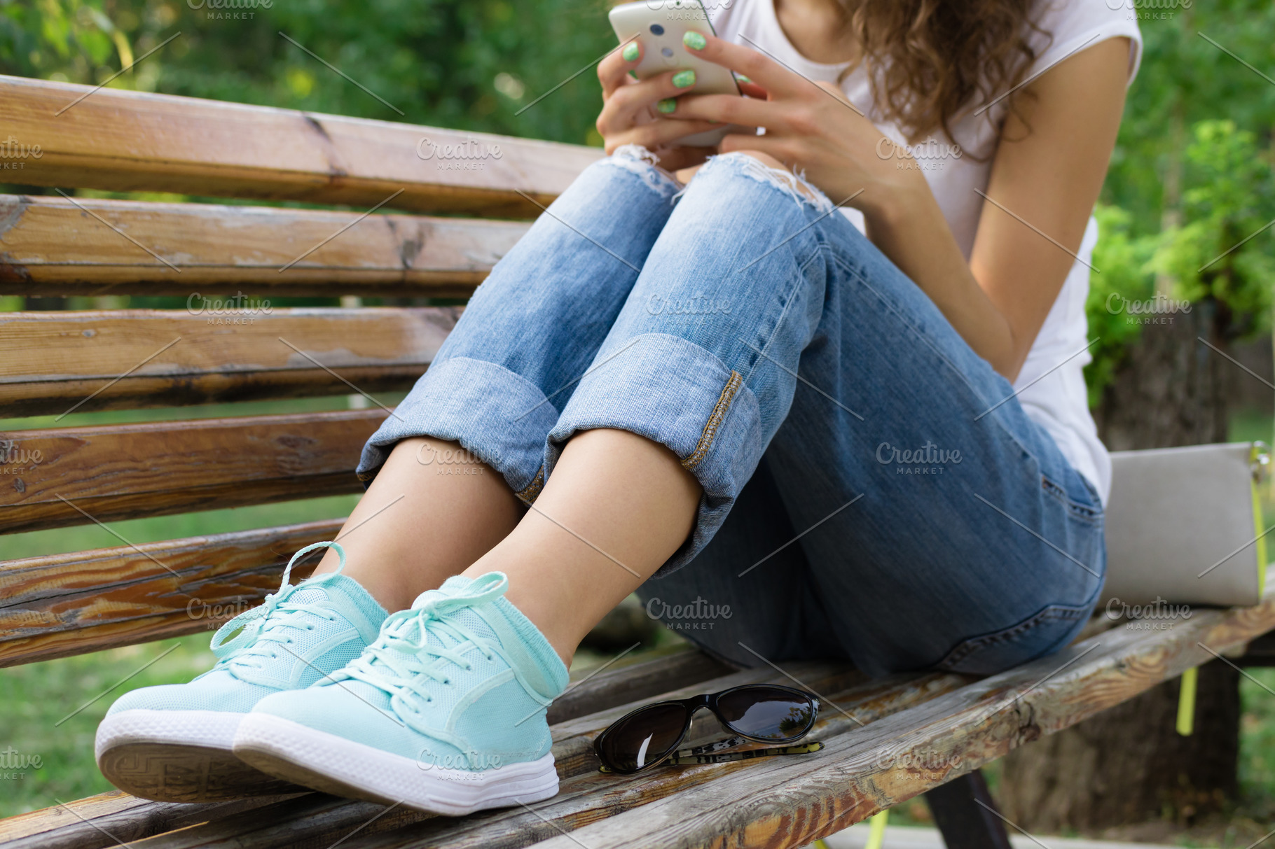 Girl in jeans sits on a park bench a | People Images ~ Creative Market