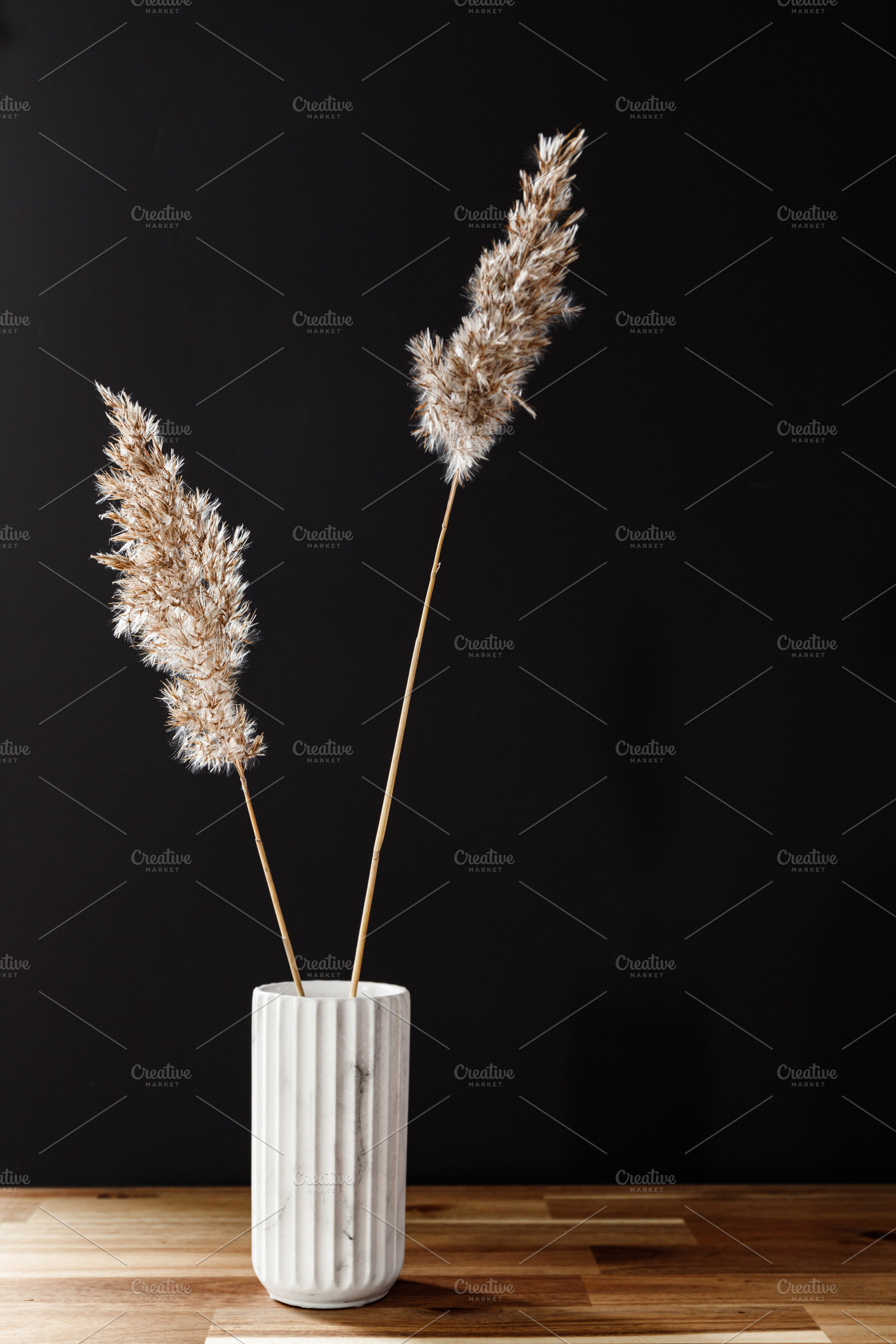 Reed in a white marble vase featuring background, grass, and table